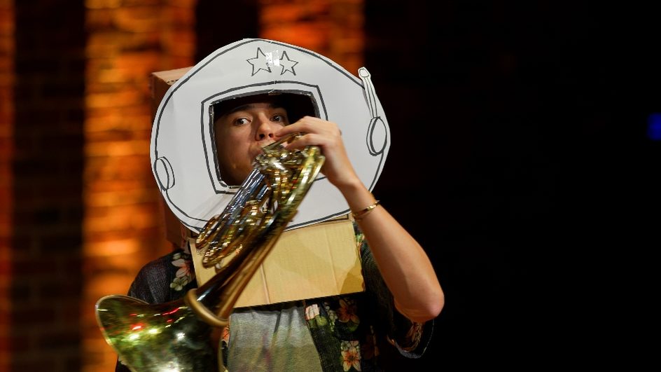 Person dressed as astronaut playing the French Horn