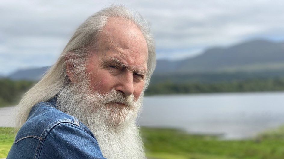 Roy Harper standing in front of a lake
